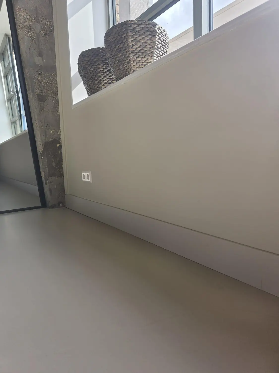 Wand, plint en gietvloer als één rustig geheel — doorlopende plintlijn